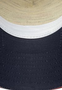 Sombrero de ala ancha con un exterior de tela en color azul marino oscuro y un interior texturizado en color beige claro. Presenta un detalle de costura blanca a lo largo del borde.