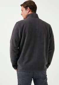 Dunkelgrauer Fleecepullover für Herren mit hohem Kragen, langen Ärmeln und einer strukturierten Stoffoberfläche. Keine sichtbaren Marken oder Muster.