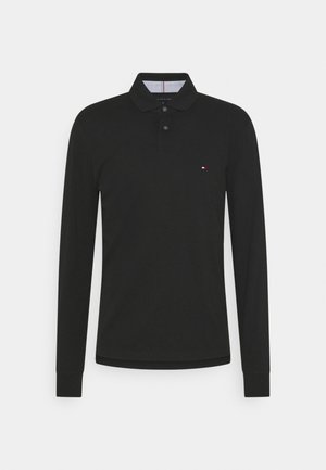 Polo à manches longues noir avec un col classique, trois boutons, et un petit logo sur la poitrine gauche. Matière en coton doux.