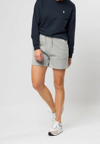 Šedé bavlněné šortky s elastickým pasem a stahovací šňůrkou, kombinované s tmavě modrým dlouhým rukávem s malým logem.