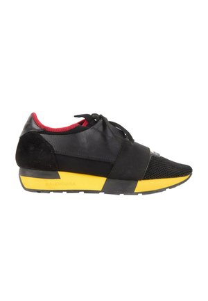 Czarno-czerwony sneaker z żółtą podeszwą, zapięciem na sznurowadła i elastycznym paskiem z przodu, zaprojektowany do codziennego noszenia.