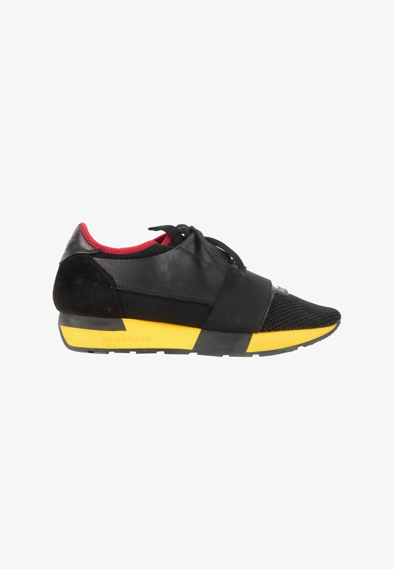 Baskets noires et rouges avec semelle jaune, fermeture à lacets et bande élastique à l'avant, conçues pour un usage décontracté.