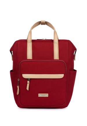 Czerwony plecak w kształcie kwadratu z beżowymi uchwytami, przednią kieszenią na zamek, bocznymi kieszeniami oraz małą etykietą marki na dole, pośrodku.