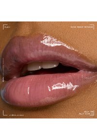 Gros plan sur des lèvres brillantes aux tons naturels, bouche légèrement ouverte montrant les dents supérieures, mettant en valeur la texture lisse et la brillance.