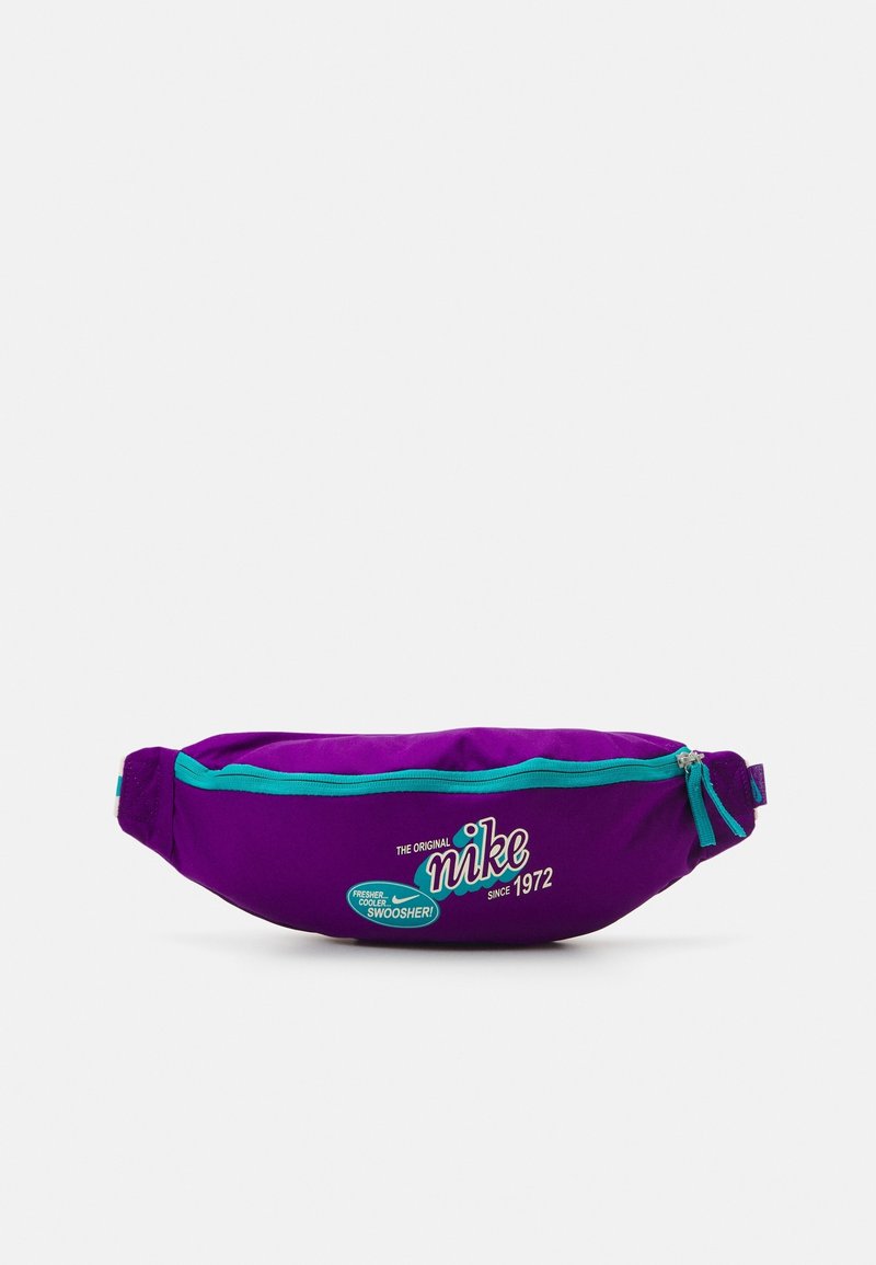 Riñonera de tela morada con cremallera y acentos en turquesa. Presenta texto de logo y fecha, equipada con un único compartimento central.