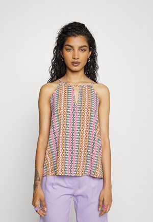 Top de halter multicolorido com um padrão geométrico, apresentando uma abertura em forma de olho de fechadura, feito de tecido leve, combinado com calças de lavanda.