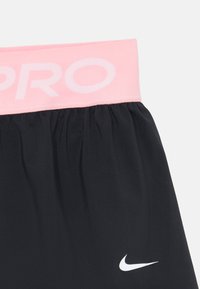 Mustad mustad püksid heleda roosa kummivöökohaga, millel on valged tähed "PRO" ja väike valge Nike logo alumises osas.