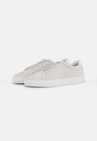 Light grey suede sneakers with a smooth texture, featuring flat laces, a rounded toe, and a white sole. Minimalist design with subtle accents.