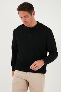 Melna garām piedurknēm polo krekls ar ribotu tekstūru, trīs pogu aizdari un mīkstu audumu. Valkāts ar bēšiem biksēm.