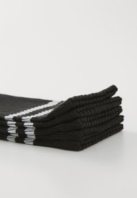 Schwarze Sportstrümpfe, die vertikal gestapelt sind, mit weißen Streifenmustern und geripptem Textur. Hergestellt aus einem weichen, dehnbaren Material.