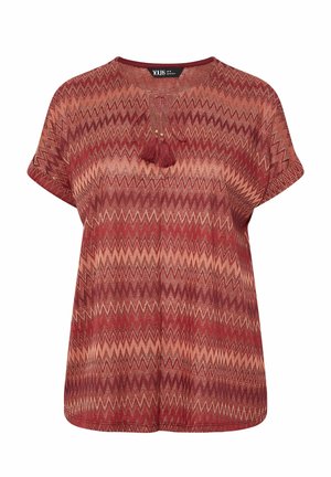 Rotes und beiges Kurzarm-Oberteil mit Zickzackmuster, Rundhalsausschnitt und einer Quaste mit kleinen Perlen vorne.