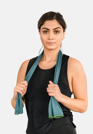 Dunkelgrünes Widerstandsband, gehalten von einer Person in einem schwarzen Netz-Top. Das Band ist strukturiert und endet mit glatter Oberfläche.