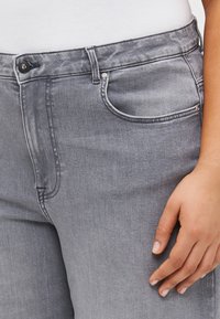 Gray denim jeans with a smooth texture, featuring a front pocket, visible stitching, and a button closure at the waist.