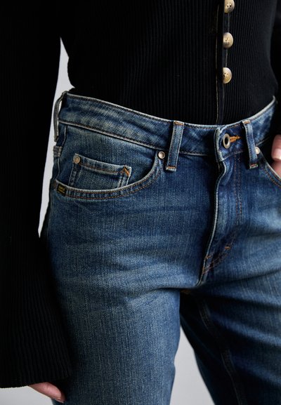 Tmavomodré džíny z denimu s vyblednutým vzhľadom, s klasickým dizajnom piatich vreciek, kontrastným prešívaním a zlatým gombíkom.