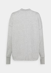 Ljust grå långärmad tröja med ribbade muddar och en central söm som går vertikalt ner längs ryggen.