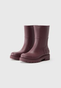 Bottines en caoutchouc bordeaux avec un bout rond, une semelle texturée et des accents sur les côtés. Design sans couture avec une base plateforme épaisse et crantée.