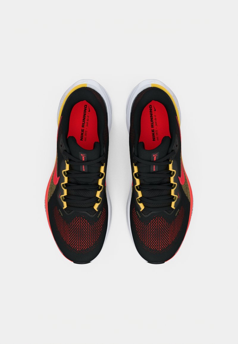 Scarpe da ginnastica nere con accenti rossi e gialli. Tomaia in rete, suola bianca spessa e lacci a contrasto. Nota logo Nike rosso sul lato.