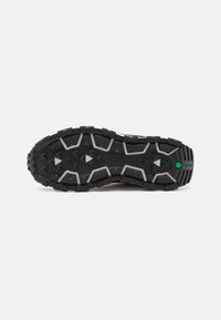 Suela de zapato de goma negra con un patrón de agarre texturizado y multidireccional; la entresuela presenta acentos grises y recortes triangulares para una mejor tracción.