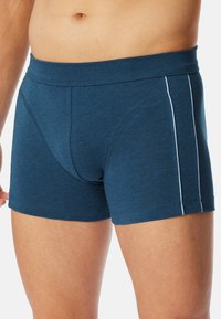 Mörkblå boxershorts i mjukt, stretchigt tyg, med ett slätt midjeband och vita sidosträck för kontrast.