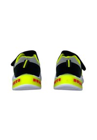 Scarpe atletiche nere e giallo neon con suola bianca, dotate di una cinghia in Velcro, tacco pronunciato e audace lettering rosso "BULLY" sul retro.