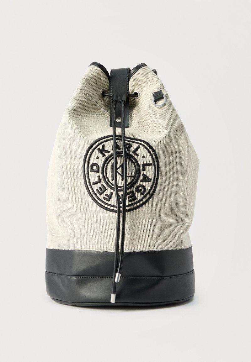 Τσάντα κουβαδάκι σε μπεζ και μαύρο με κορδόνια, με κυκλικό λογότυπο Karl Lagerfeld στο μπροστινό μέρος και κορδόνια με μεταλλικές άκρες.