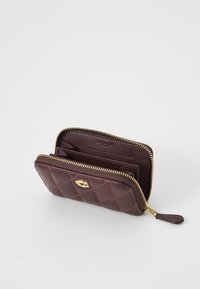 Burgundy quilted leather wallet with gold hardware, zip closure, multiple card slots, and interior pocket for coins.