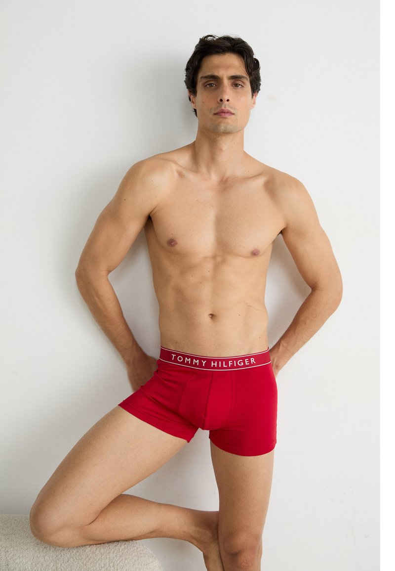 Punased boksershortsid, mille must-valge vöökoht on särgi peal "TOMMY HILFIGER" tekst. Kangas näeb välja sile ja keha külge liibuv.