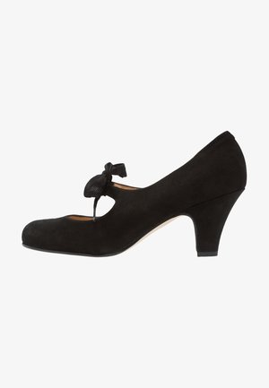 Chaussure à talon haut en daim noir avec un bout arrondi, un design découpé et un accent en nœud en tissu, présentant un talon de hauteur moyenne.