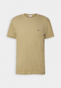 T-shirt beige en coton à manches courtes avec col rond et petit logo crocodile vert sur la poitrine gauche.