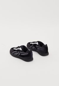 Čierne športové topánky s bielymi akcentmi, s semišovou textúrou, s viazaním, zaobleným tvarom a vzorovanou gumovou podrážkou.