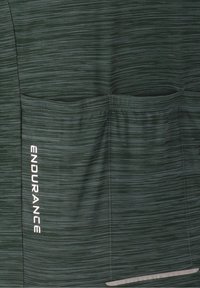 Tissu gris foncé avec de fines rayures horizontales, trois poches cousues, mot "ENDURANCE" imprimé verticalement sur la poche gauche.
