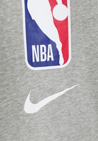 Sudadera gris con un gran logo de la NBA en rojo y azul, con un logo de Nike en blanco debajo. Tejido suave y texturizado.