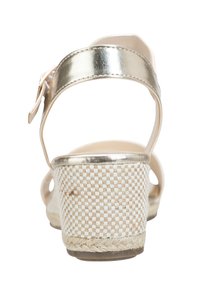 Sandales à bride arrière métalliques dorées avec un talon tissé beige. Surface texturée avec un motif et une bordure en jute le long du bas.
