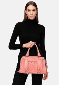 Borsa in suede rosa con doppi manici superiori, hardware in metallo, tasca frontale con zip e design plissettato. Texture liscia con una leggera lucentezza.