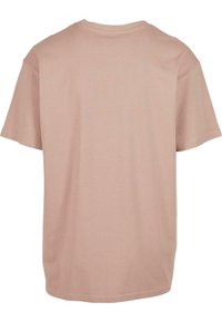 Tricou cu mânecă scurtă dintr-un material moale de piersici. Design cu gât rotund, croială lejeră, cusături netede la tivuri și fără modele sau grafică vizibilă.