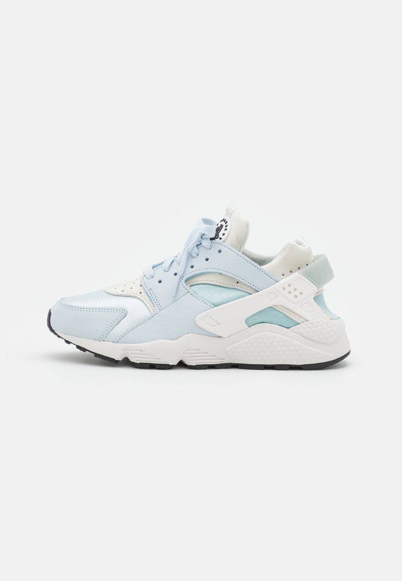 Basket de sport bleu clair et blanc avec mesh, panneaux en cuir, lacets sur le devant et semelle épaisse texturée, vue de côté sur fond blanc.
