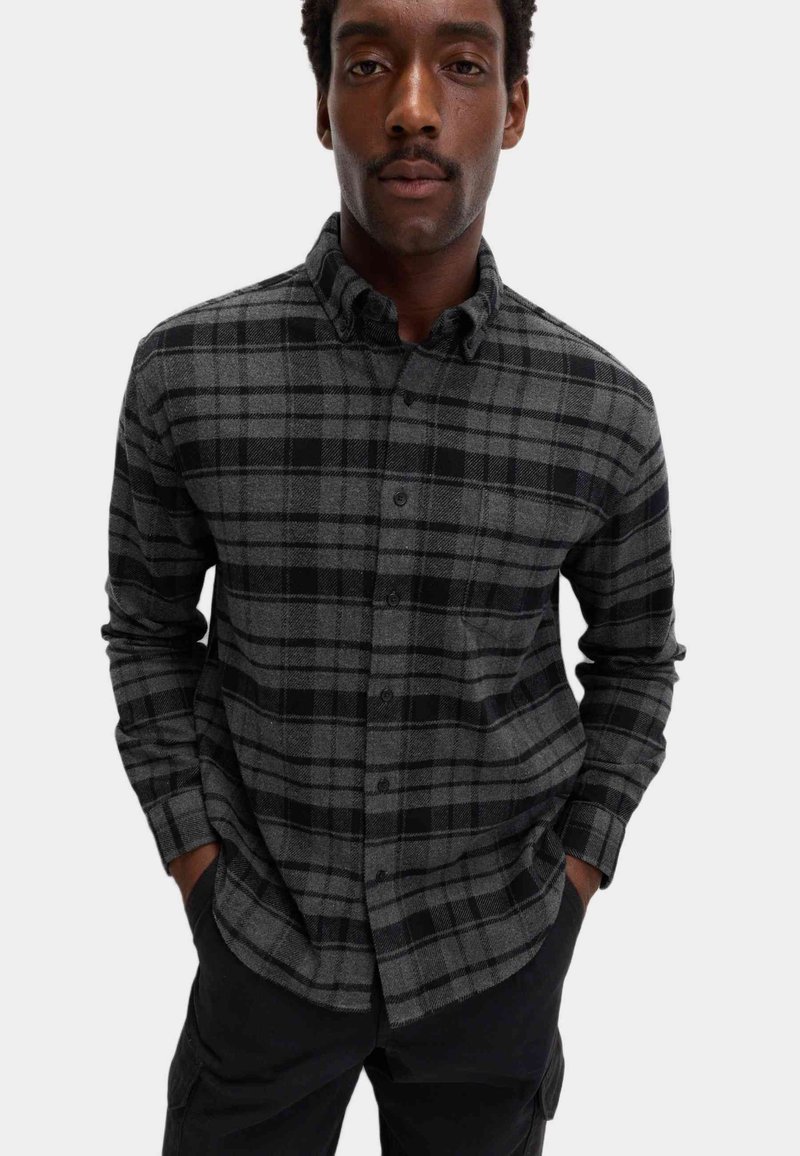 Zwart en grijs geruite flanellen overhemd met een button-down kraag en lange mouwen. Voorzien van een zak aan de linkerkant.