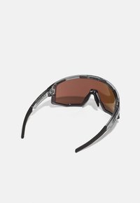 Sport sunglasses with a semi-transparent gray frame, brown lenses, and black arms. Angular design with clear accents and branding detail.
