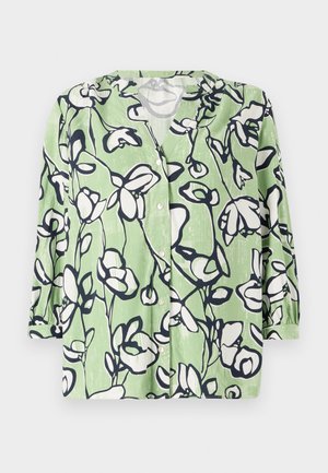 Zeleni srajčni gumbnjak z cvetličnim vzorcem v beli in modri barvi. Ima V-izrez in rokave do tri četrtine z gladko teksturo.