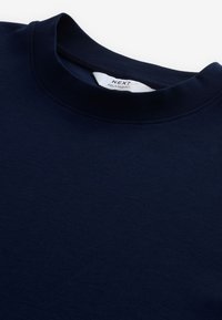 Camiseta de corte relajado en azul marino, hecha de suave tela de algodón, con un cuello redondo tipo crew, sin patrones ni adornos.