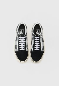 Black and white checkered canvas sneakers with black suede toe cap and white laces. Features a black inner lining and logo on the tongue.