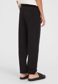 Svarta sweatpants med avslappnad passform, som har ett elastiskt midjeband och avsmalnande ärmslut. Tillverkade av mjukt, lätt material.