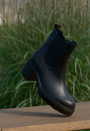 Schwarze Stiefelette aus glattem Leder, mit elastischen Seitenpaneelen und einem kräftigen Absatz. Zu den Details gehören dezente Nähte und eine strukturierte Sohle.