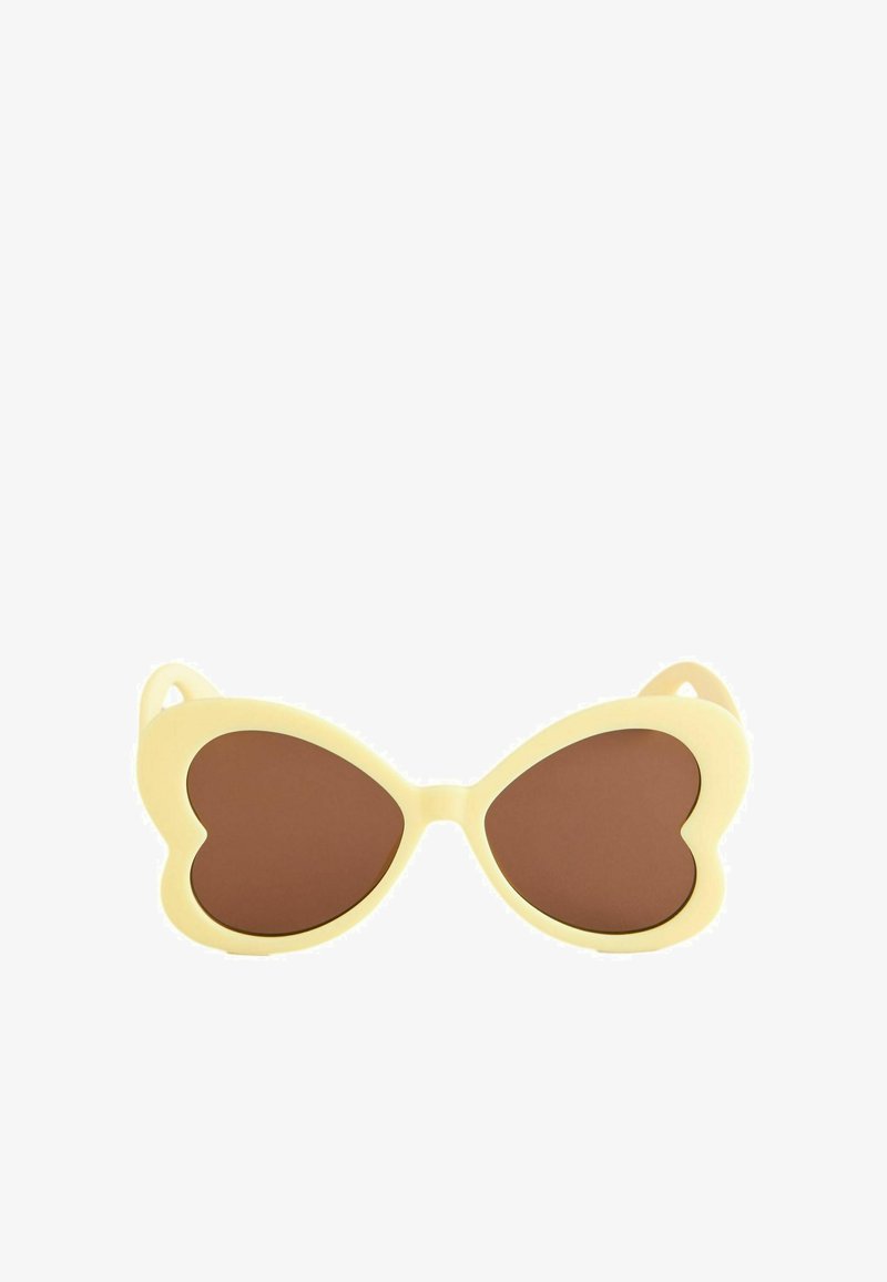 Lunettes de soleil couleur crème avec des verres marron en forme de cœur, présentées sur un fond blanc.