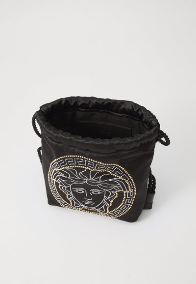 Svart satin dragkedjesäck med en slät yta, prydd med en Medusa-emblem utsmyckad med guld- och silvernitar.