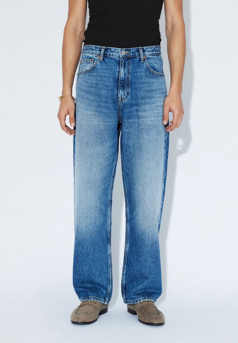 Jeans in denim azzurro chiaro con design a gamba larga, lavaggio medio, texture sbiadita sul davanti e classica vestibilità a cinque tasche.