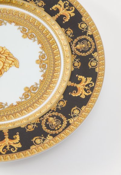 Porcelánový tanier s centrálnym motívom leva, čiernym pozadím a zložitými zlatými detailmi. Obsahuje ozdobné vzory a lesklý povrch.