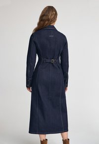 Jeans trenchcoat, mörkblå, med bälte i midjan, långa ärmar med knappfästen, ryggsömmar, synlig sömnad, ankel-lång.