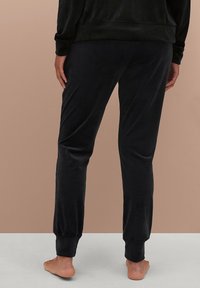 Zwarte velours joggingsbroeken met elastische boorden en een ontspannen pasvorm, met een gladde textuur en geen zichtbare patronen of hardware.