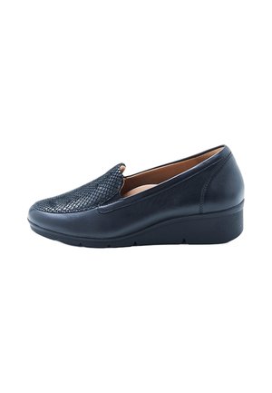 Zapato negro de cuero sin cordones con parte delantera texturizada y tacón de cuña bajo, diseñado para comodidad y uso informal.